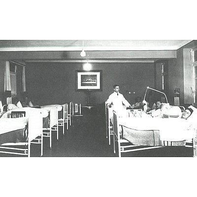 Schwarzweiß Bild eines Krankenzimmers mit Betten und Patienten und einem Arzt 
